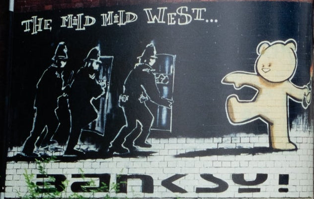 Open book showing a street scene with a prominent 'Banksy' mural.