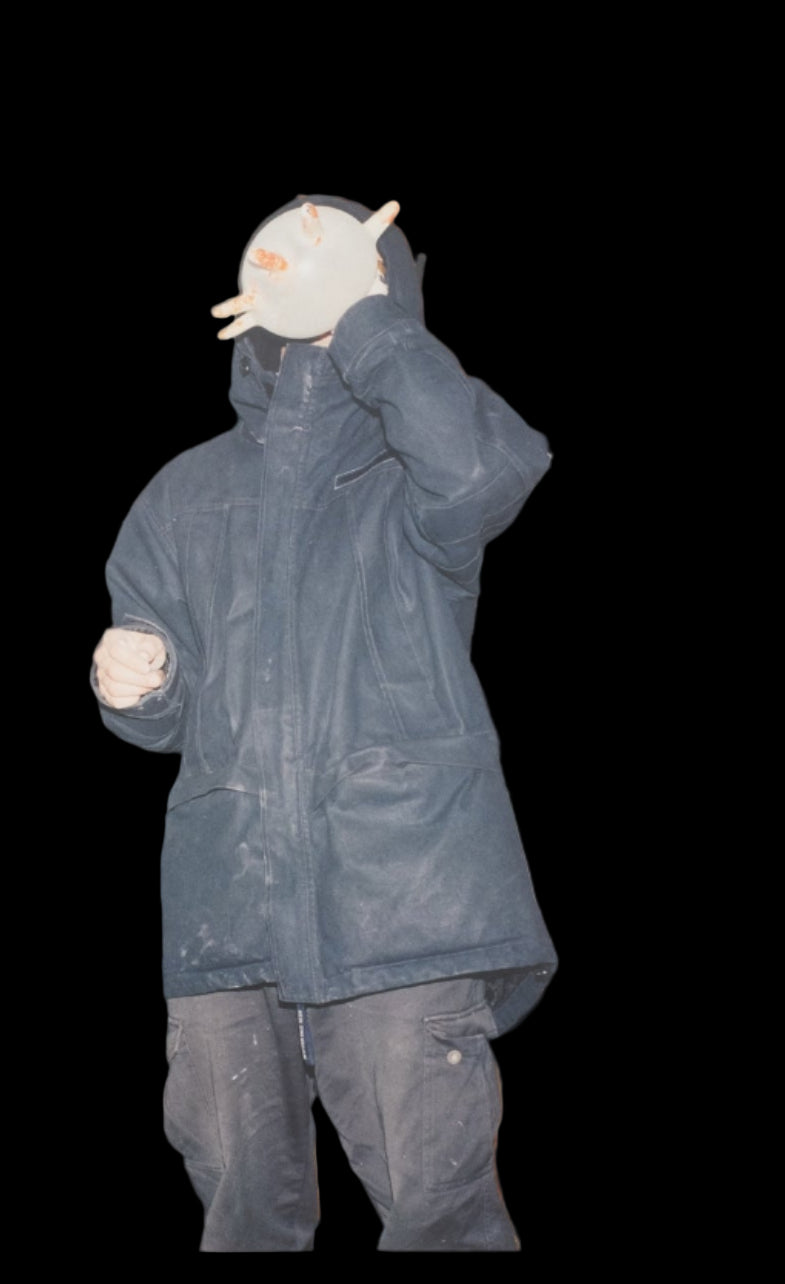 Person wearing a blue raincoat and holding a white mask with a black background